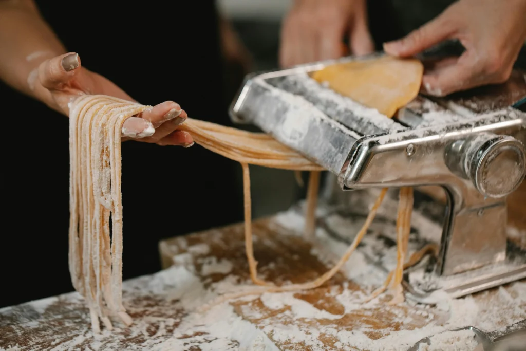 Rolling out fresh pasta dough on a lightly floured surface using a rolling pin, capturing the essential step of rolling the dough for perfect Italian pasta.